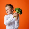 Boy holding head of broccoli                               